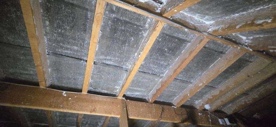 Original spray foam insulation before removal in a UK loft space